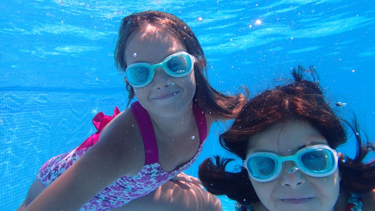 Dos niñas bañándose en una piscina. Foto subacuática.